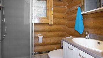 Ein Badezimmer mit einer Holzvertäfelung, einem weißen Waschbecken, einem Spiegel und einer Toilette.