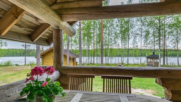 A wooden deck with a table and chairs, overlooking a lake and forest. - Aurinkoniemi by Interhome (Hankasalmi)