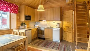 A wooden cabin-style kitchen with a dining table, chairs, a stove, oven, microwave, and dishwasher.
