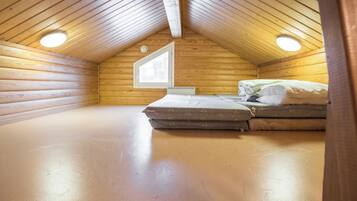 Um quarto pequeno com telhado inclinado, uma cama e um claraboia.
