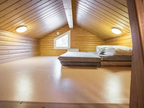 Um quarto pequeno com telhado inclinado, uma cama e um claraboia.