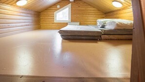 A small, wooden-paneled attic bedroom with a single bed and a skylight.