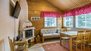 A cozy cabin interior with a fireplace, wooden furniture, and large windows.