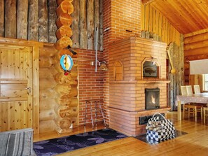 A log cabin interior with a fireplace, wooden walls, and a dining area.