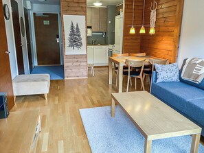 A compact living space with a sofa, a wooden table, a small kitchenette, and a dining area. - Ylläs chalets a307 by Interhome (Ylläsjärvi)