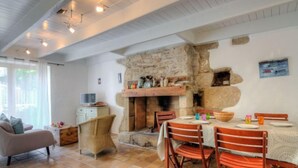 A cozy dining area with a stone fireplace, wooden chairs, and a tiled floor. - Vacation home Hoche by Interhome (Quiberon)