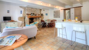 A cozy living room with a fireplace, a dining area, and a kitchen with bar stools. - Vacation home Hoche by Interhome (Quiberon)