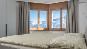 A bedroom with a bed, large windows, and a view of mountains. - Zurschmitten 12 1. UG Süd by Interhome (Riederalp)