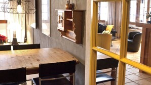 En matplats med ett träbord och stolar, en hängande lampa och ett väggmonterat skåp.