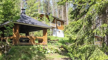 Une cabane avec une façade en bois, une véranda et une terrasse.