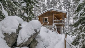 Eine Holzhütte, umgeben von schneebedeckten Bäumen.