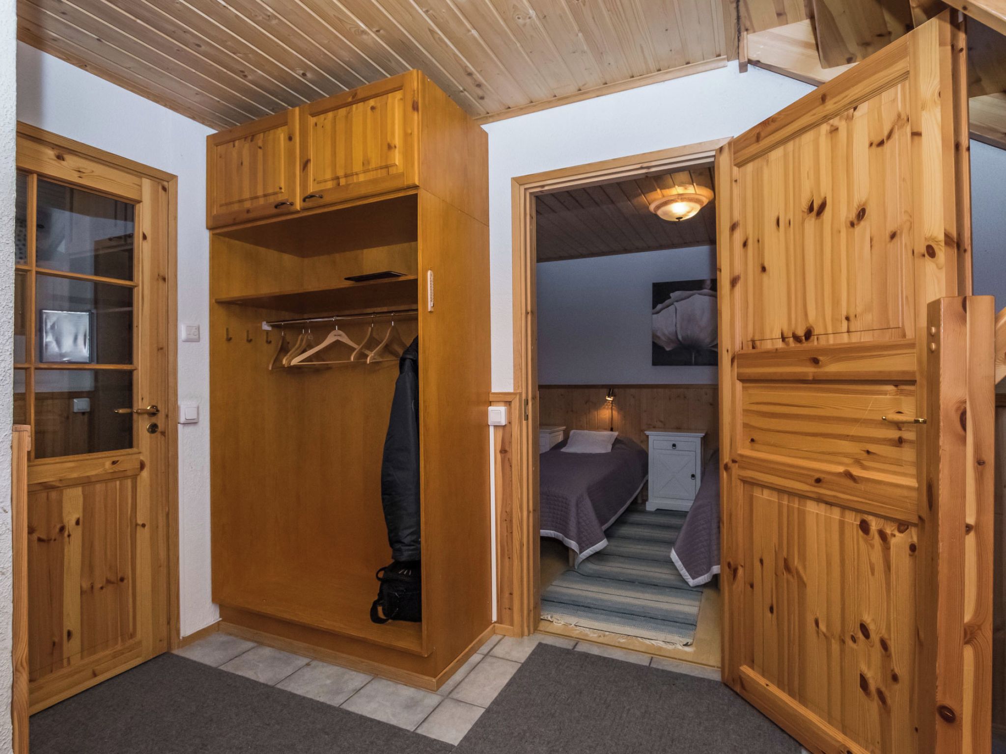 Una habitación con un armario de madera, una cama y una mesita de noche.