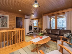 L’intérieur chaleureux d’un chalet avec un plancher en bois, une cheminée, un canapé et une table à manger.