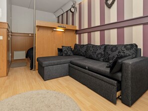 Ein modernes Wohnzimmer mit einer Eckcouch, einem Holzschrank und einer Wanduhr.