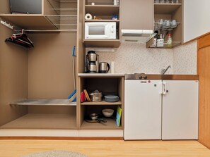 Eine kompakte Küchenzeile mit Mikrowelle, Kaffeemaschine und kleinem Kühlschrank.