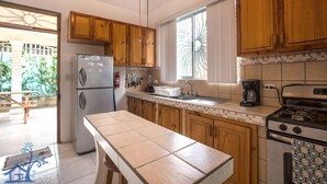 Eine Küche mit Holzausstattung, einem Edelstahlkühlschrank, einem Gasherd und einem Fenster mit Ziergardinen.