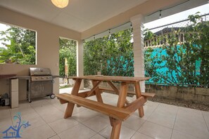 Enjoy al fresco dining on the patio, surrounded by lush greenery and a sparkling pool.