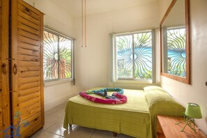 Guests can relax in this serene space with a comfortable bed, a wooden wardrobe, and a convenient nightstand.