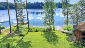 Una propiedad junto al lago con muelle de madera, una cabaña pequeña y césped.