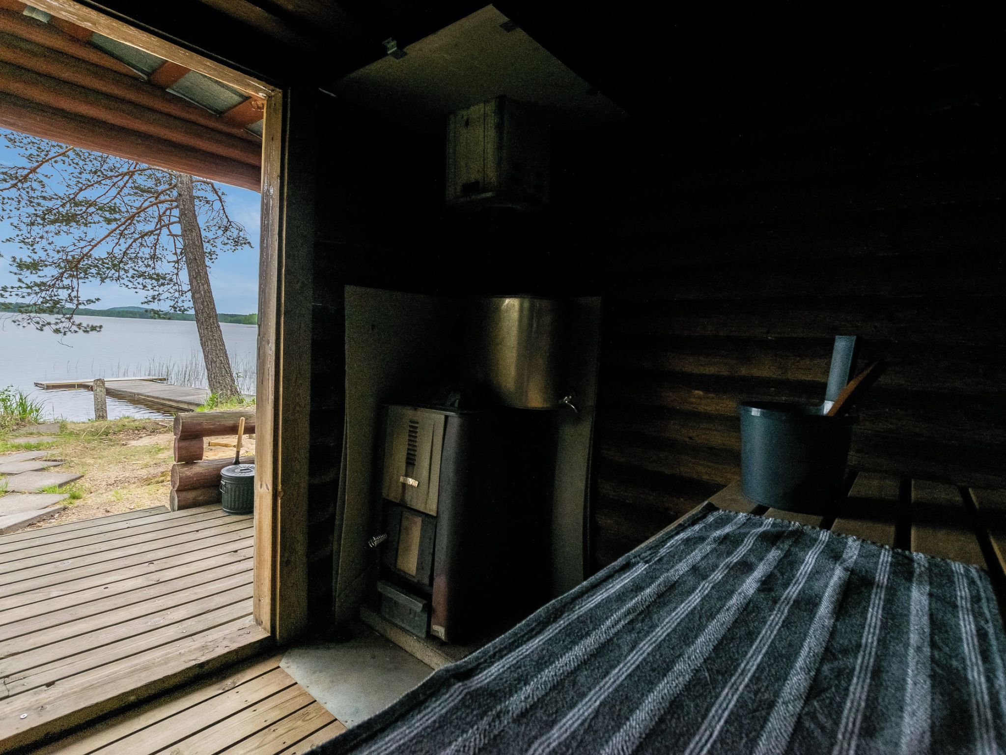A cabin with a wooden deck, a fireplace, and a view of a lake.