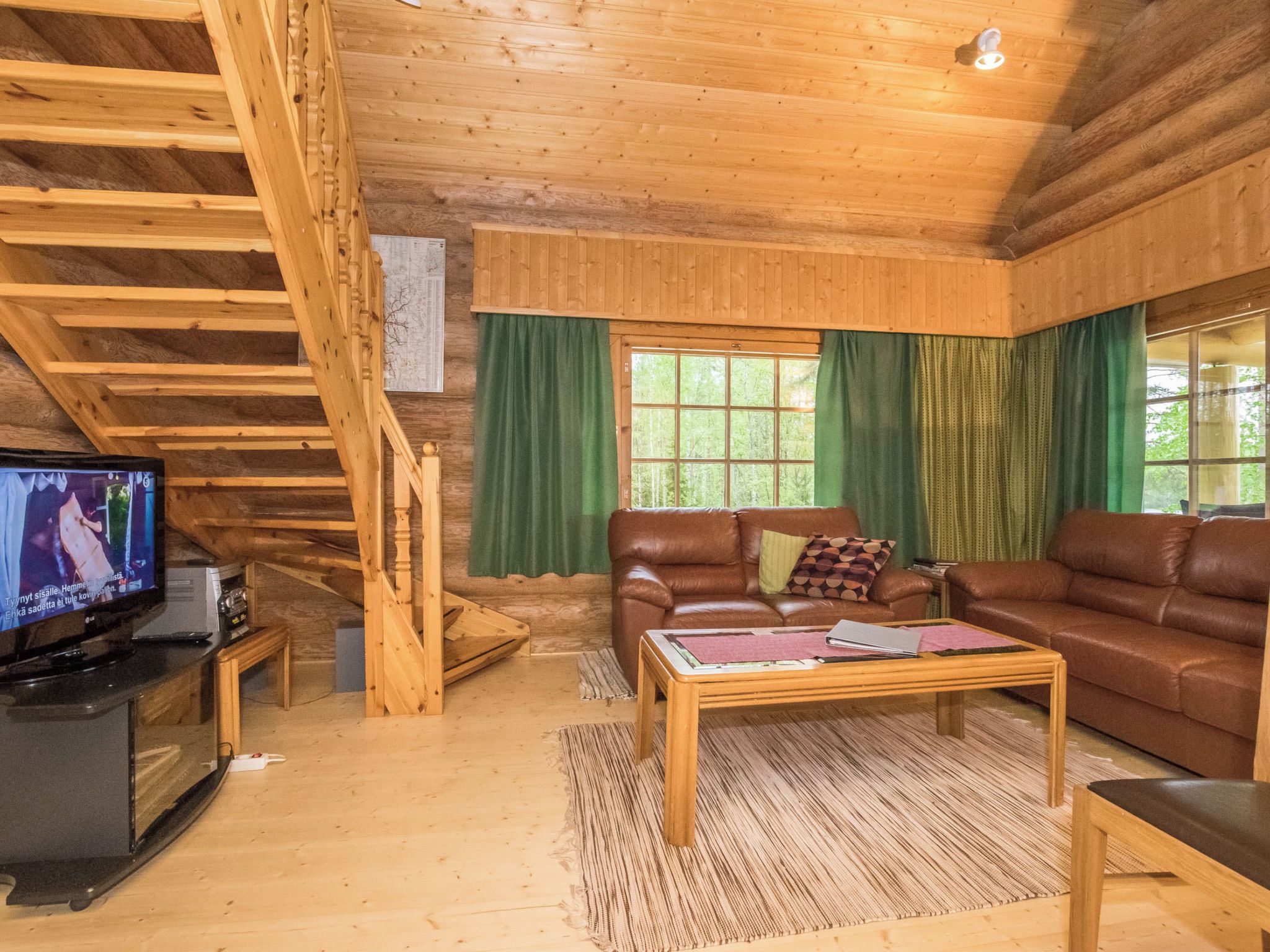 Un interior de madera con una escalera, un televisor, un sofá y una mesa de centro.