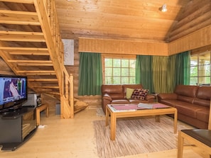 Un interior de madera con una escalera, un televisor, un sofá y una mesa de centro.