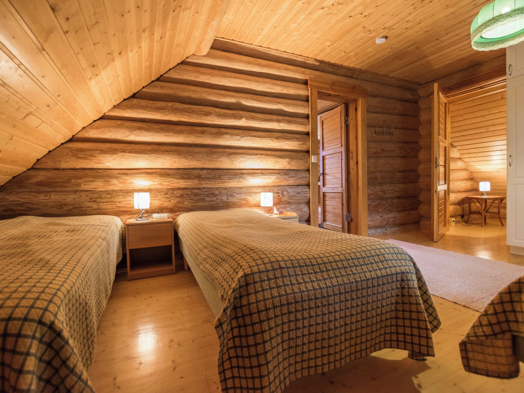Un dormitorio acogedor en el ático con dos camas, paredes de madera y techo inclinado.