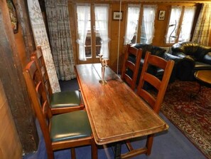 Une table de salle à manger en bois, quatre chaises, un lustre et un tapis à motifs.