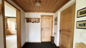 En hall med trädörrar, en klädhängare och en papperskorg.
