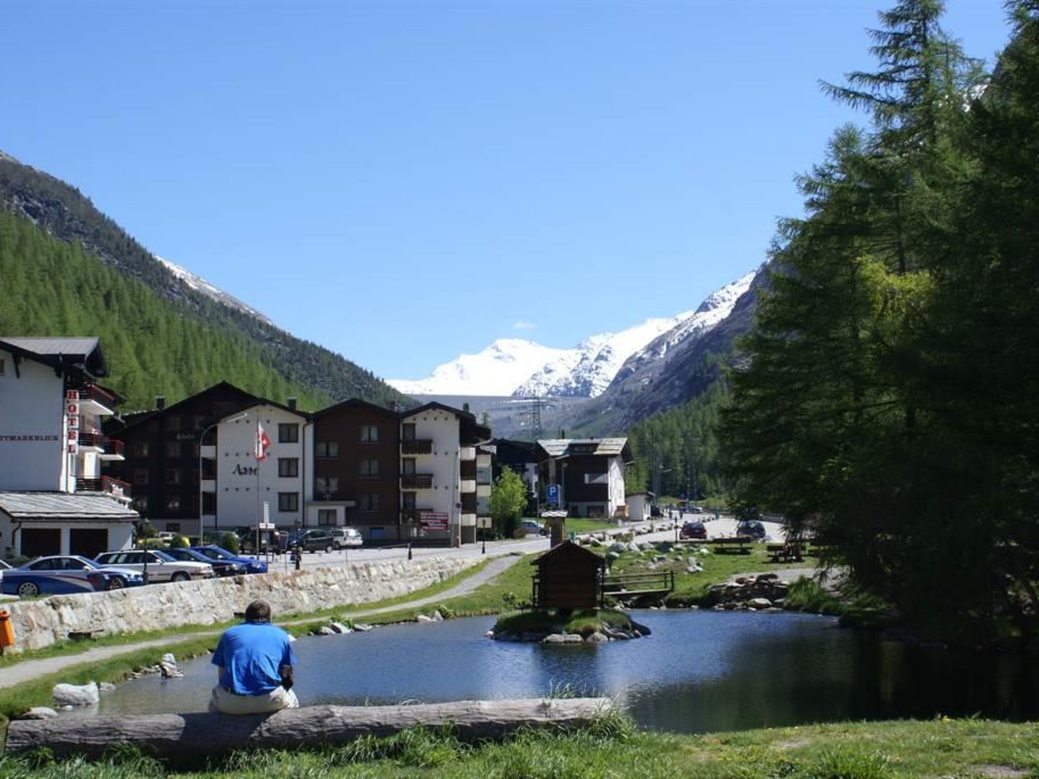 Ein Hotel mit mehreren Gebäuden, einem Parkplatz und einem See mit einer kleinen Insel.