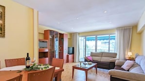 A living room with a dining area, a sofa, a television, and a cabinet. - La Goleta by Interhome (Benidorm)