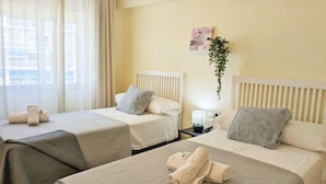 A hotel room with two beds, each with a white headboard, a bedside table with a lamp, and a window with curtains. - La Goleta by Interhome (Benidorm)