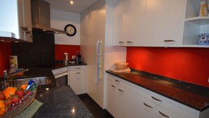 Una cocina moderna con armarios blancos, encimera de granito y una pared de acento roja.