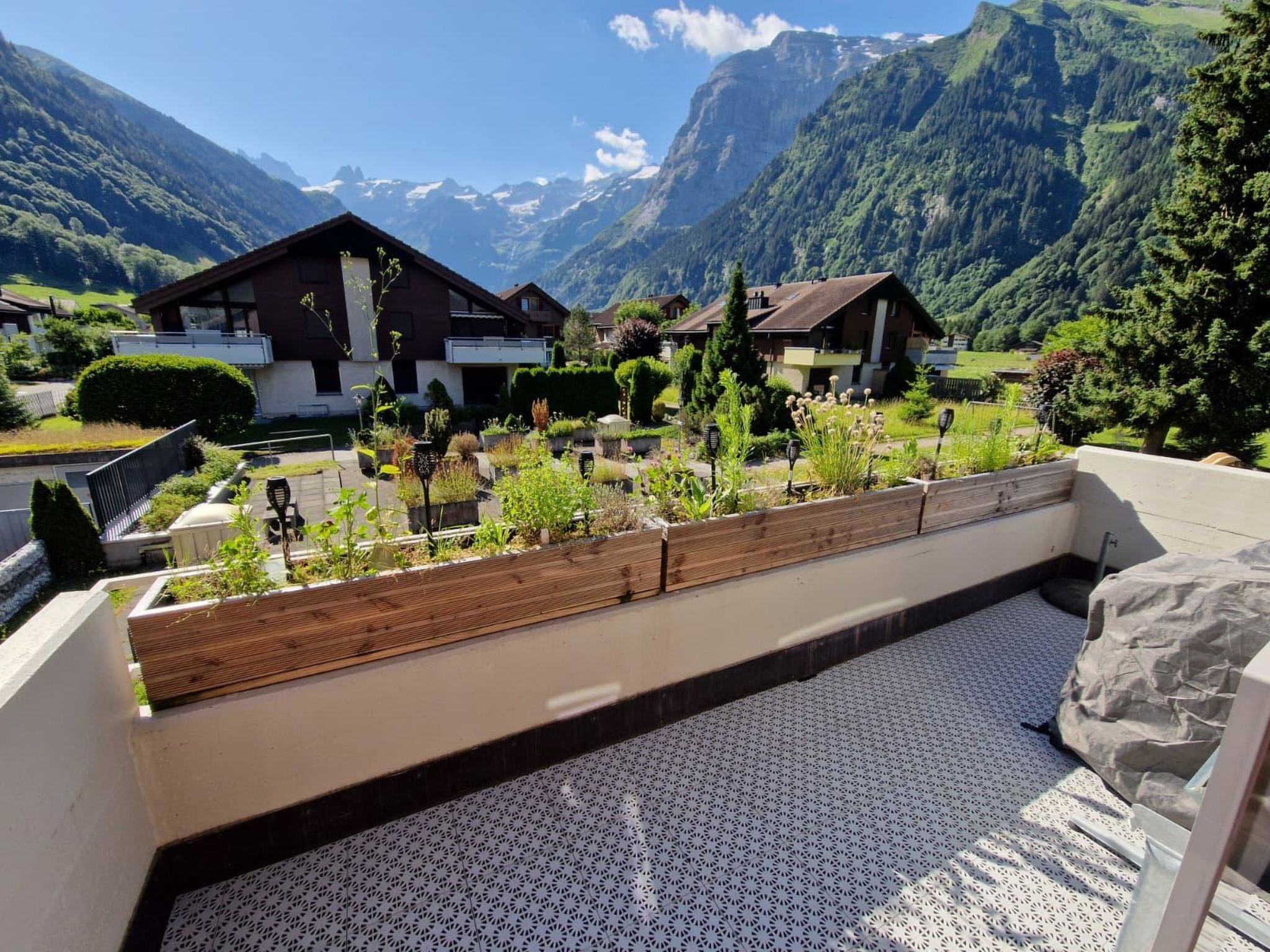 Un balcon avec vue sur les montagnes, une terrasse en bois et un sol à motifs.