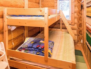 A wooden bunk bed with a ladder, a small chair, and a window with a view of trees. - Rukan lepolinna b by Interhome (Kuusamo)