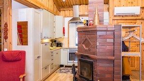 A cozy cabin interior with a kitchen, a red chair, and a fireplace.