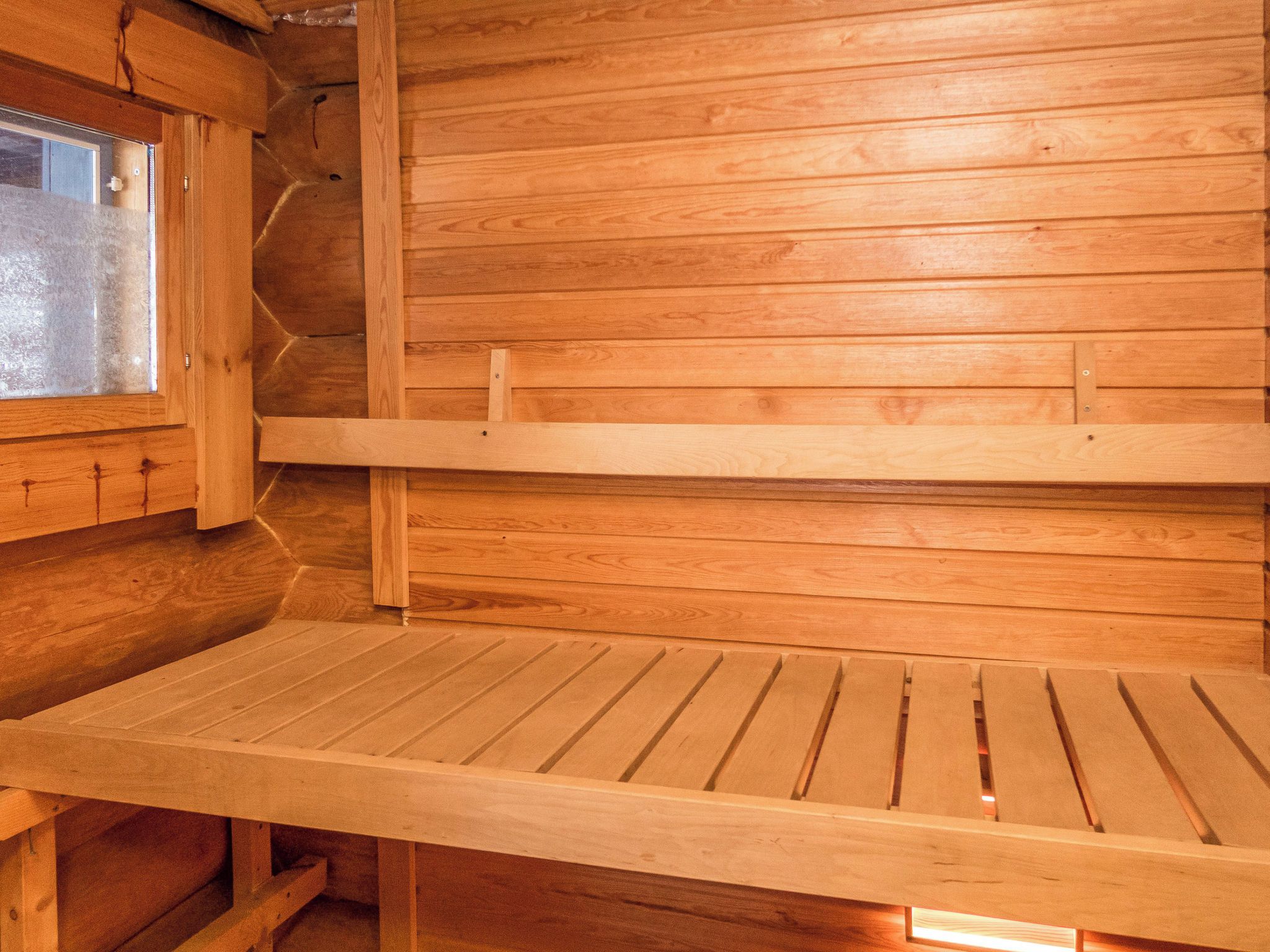 A wooden interior with a bench and a window.