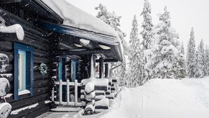 A log cabin with a snow-covered porch and a wooden fence.