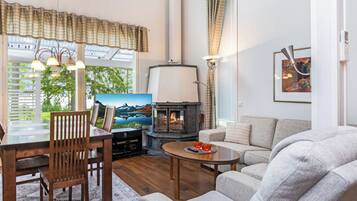 A cozy living room with a fireplace, a dining area with a table and chairs, and a sofa.