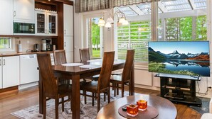 Una cocina moderna con armarios blancos y un comedor con un ventanal que da a un paisaje pintoresco.