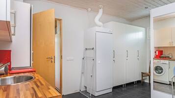Une cuisine compacte dotée d’un plan de travail en bois, d’un évier, d’un réfrigérateur blanc, d’un lave-linge et d’un meuble avec un porte-serviettes.