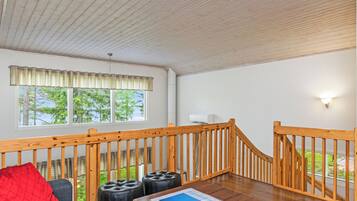 A room with a wooden staircase, a sofa, ottomans, and a table with a magazine.