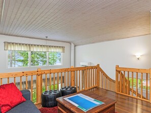 Een kamer met een houten trap, een bank, poefjes en een tafel met een tijdschrift.