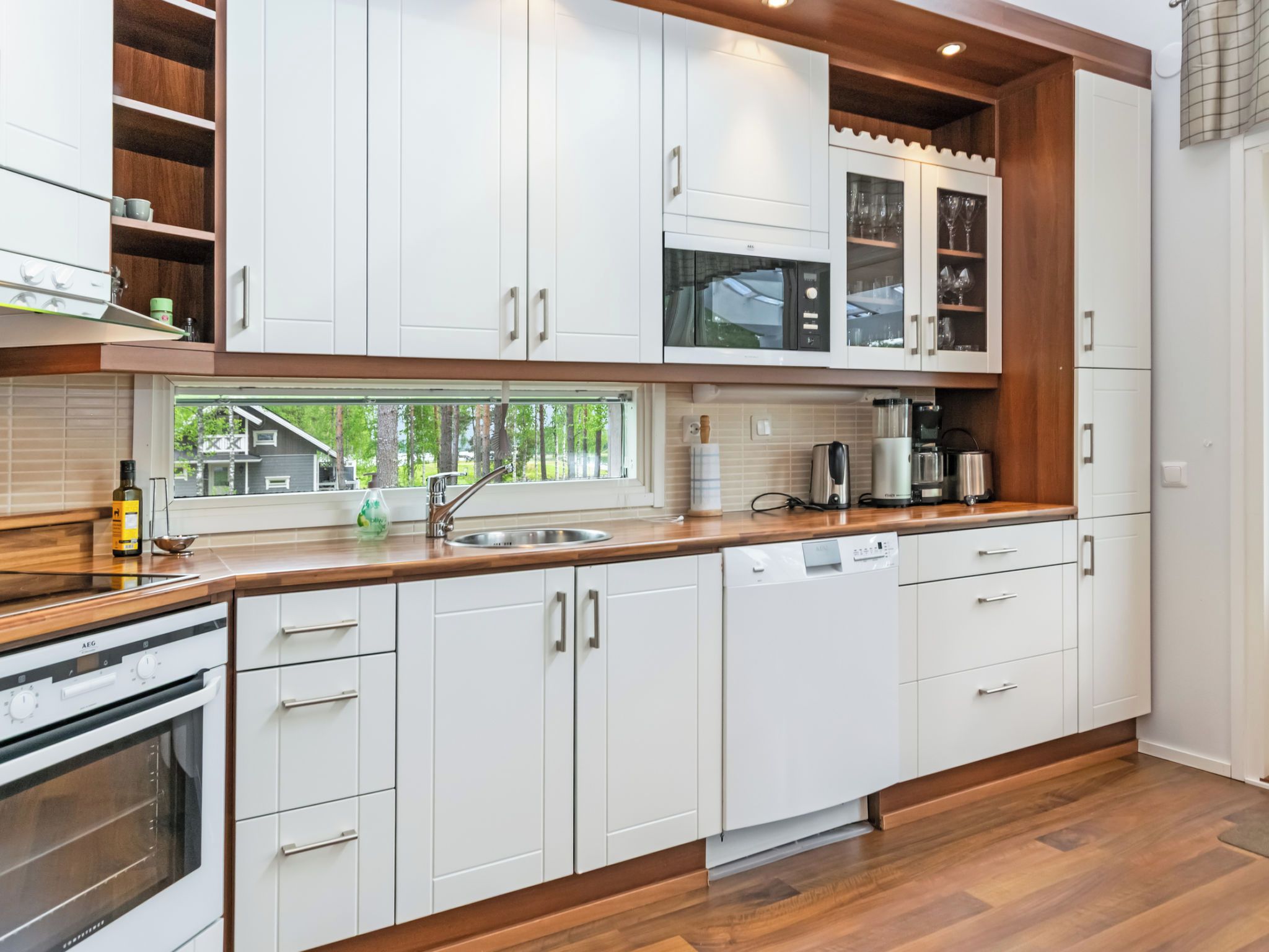 A modern kitchen with white cabinetry, a built-in oven, and a dishwasher.