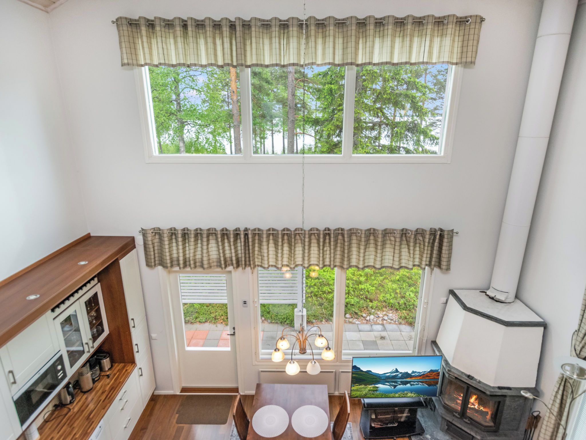 A cozy room with a fireplace, a television, and a dining area with a view of greenery outside.