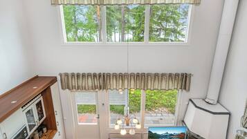 A cozy room with a fireplace, a television, and a dining area with a view of greenery outside.