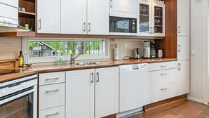 Una cocina moderna con armarios blancos, encimera de madera y horno empotrado.