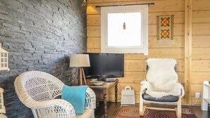 A cozy room with a brick wall, a television, wicker chairs, a lamp, and a patterned rug. - Villa vuosku by Interhome (Enontekiö)