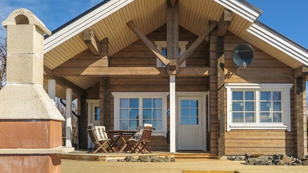 A wooden cabin with a covered porch, a fireplace, and a dining area with chairs. - Villa vuosku by Interhome (Enontekiö)
