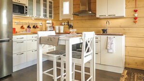 A modern kitchen with white cabinetry, a stainless steel refrigerator, a microwave, and a gas stove. - Villa vuosku by Interhome (Enontekiö)